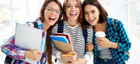 Three teenage women smiling with study notes and text books